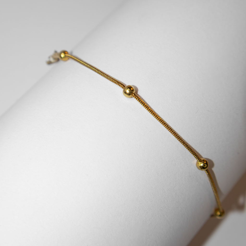 Elegant fine gold bracelet with minimalist design photographed from an alternative angle

