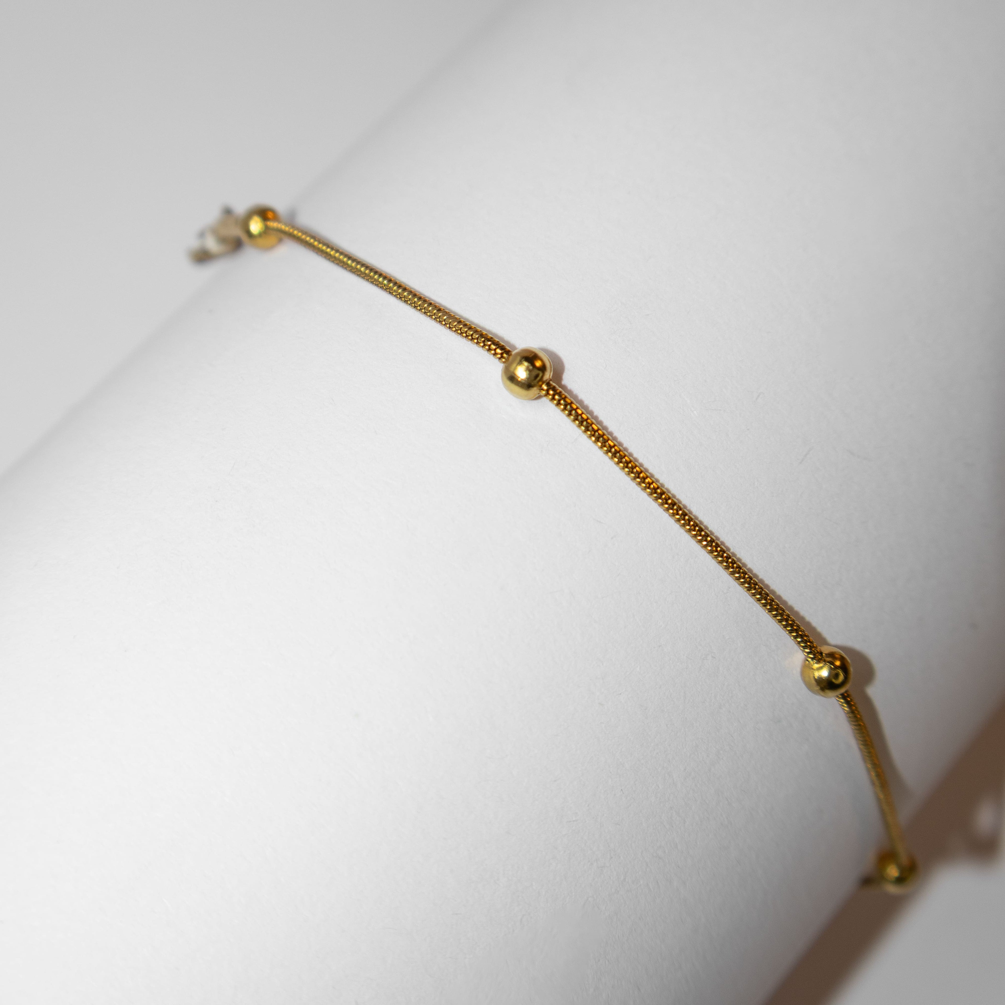 Elegant fine gold bracelet with minimalist design photographed from an alternative angle
