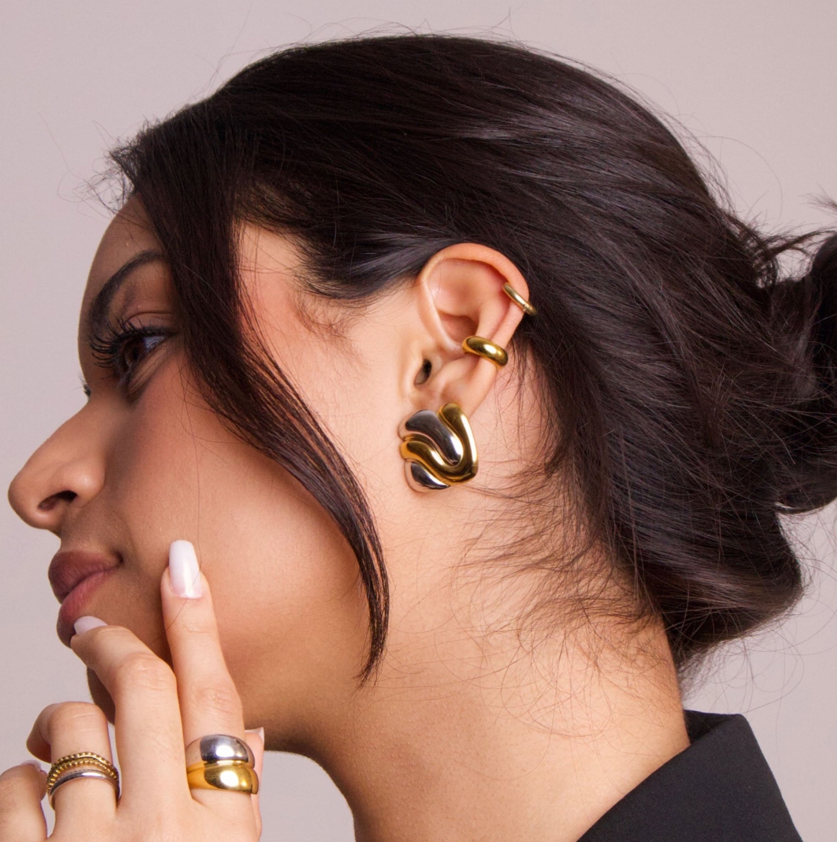 Gold ear cuff worn on ear with sculptural design, showing fit and placement

