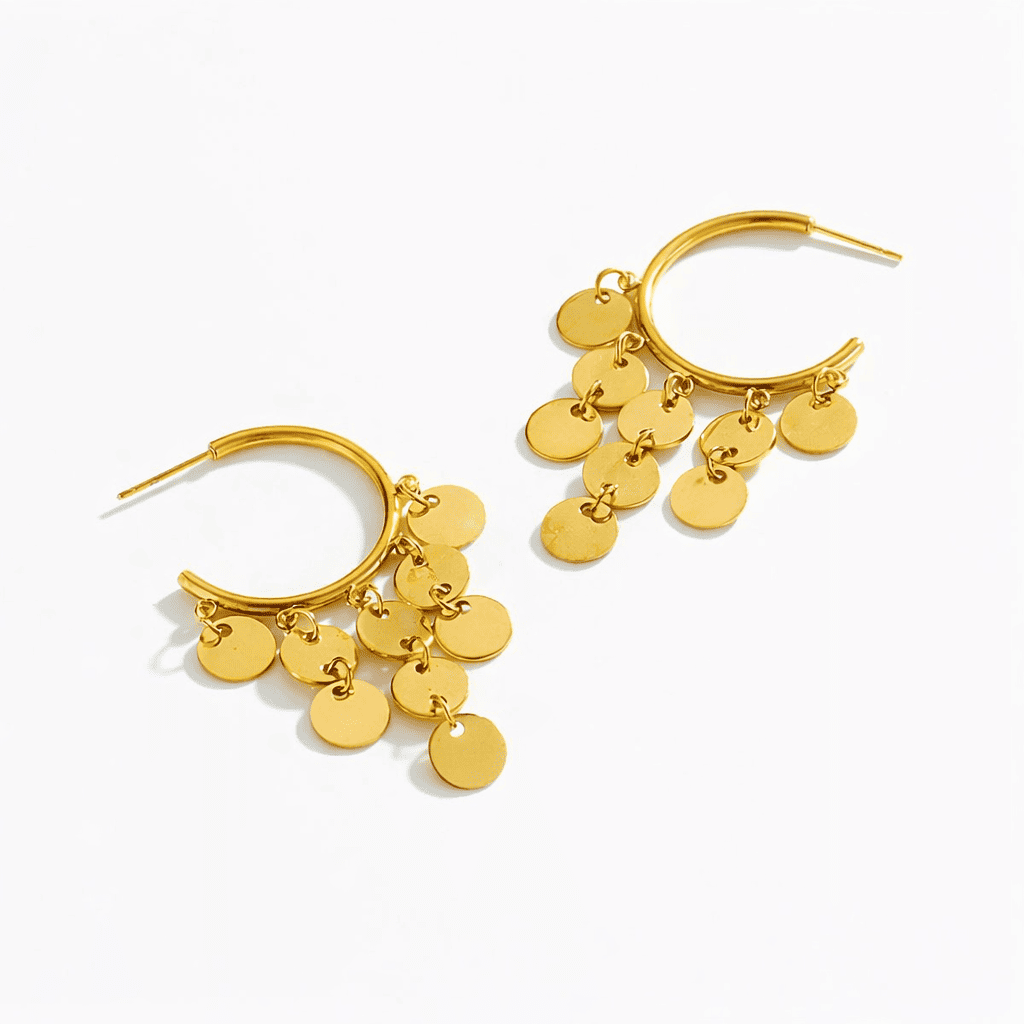 Gold hoop earrings with small dangling disc charms in a minimalist design on a white background
