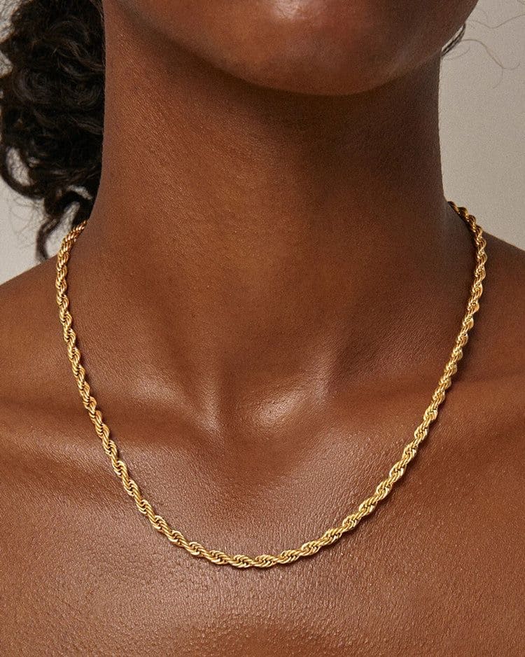 Gold rope chain necklace worn on the neck with polished twisted links
