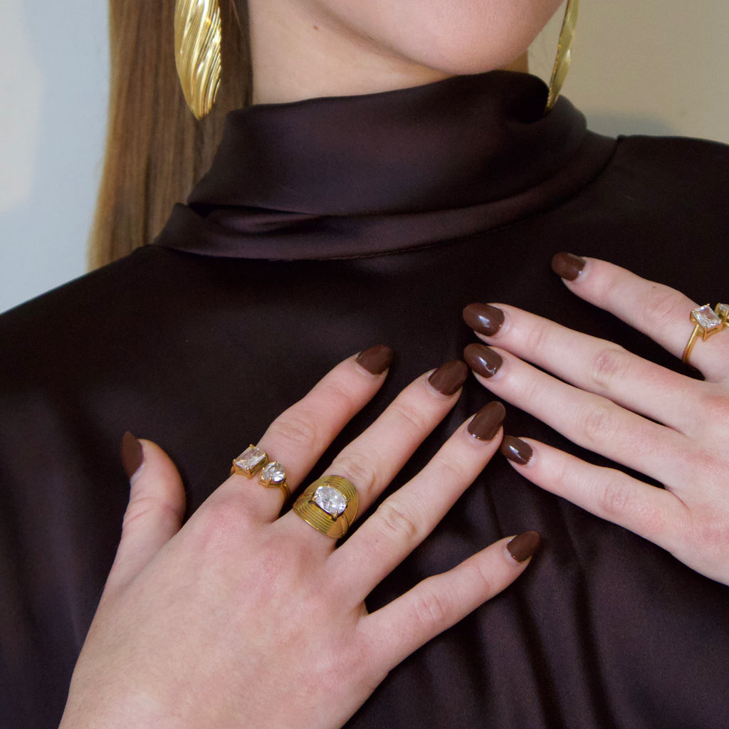 Model styling a gold crystal statement ring with a contemporary sculptural design
