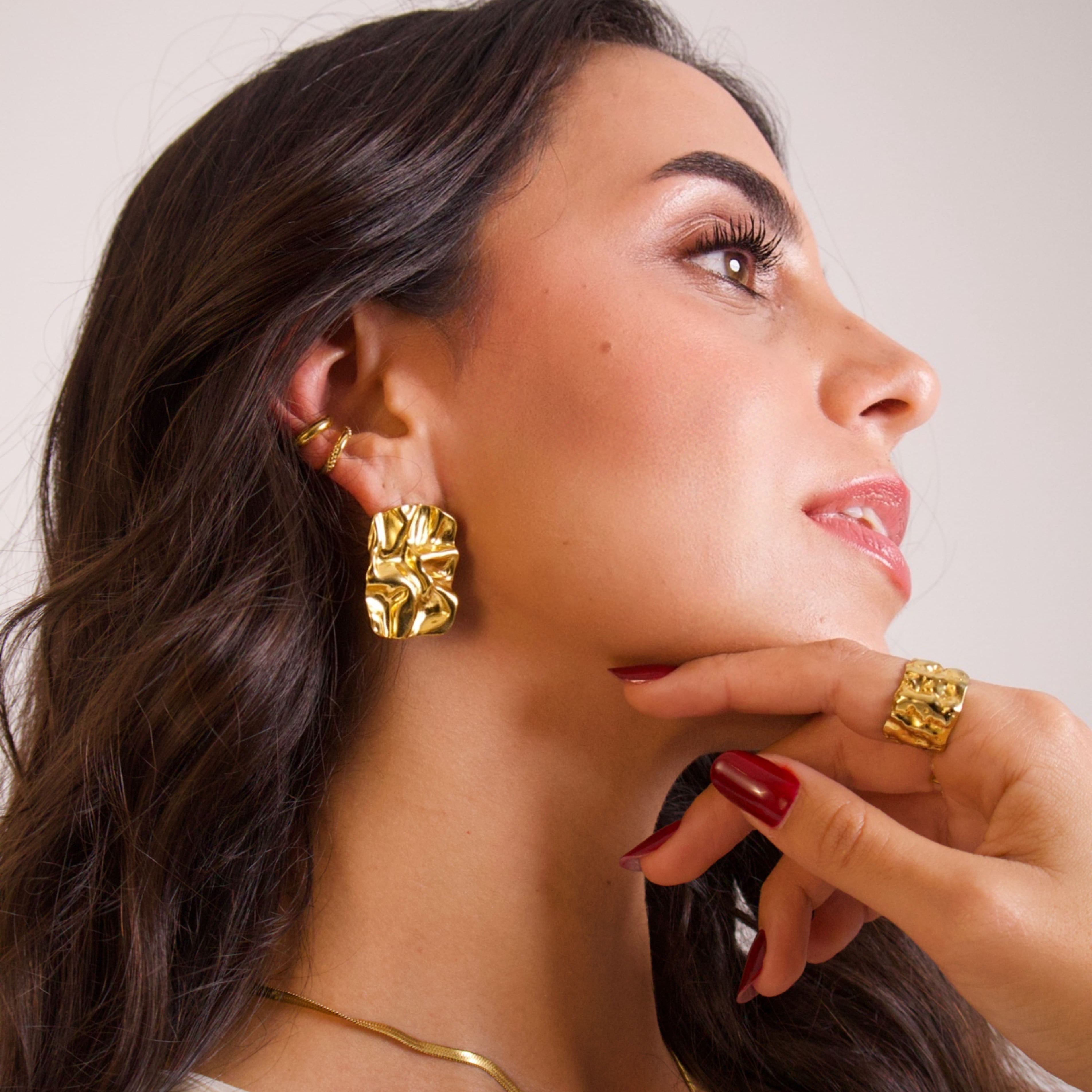 Sculptural gold statement earrings worn on model with polished finish
